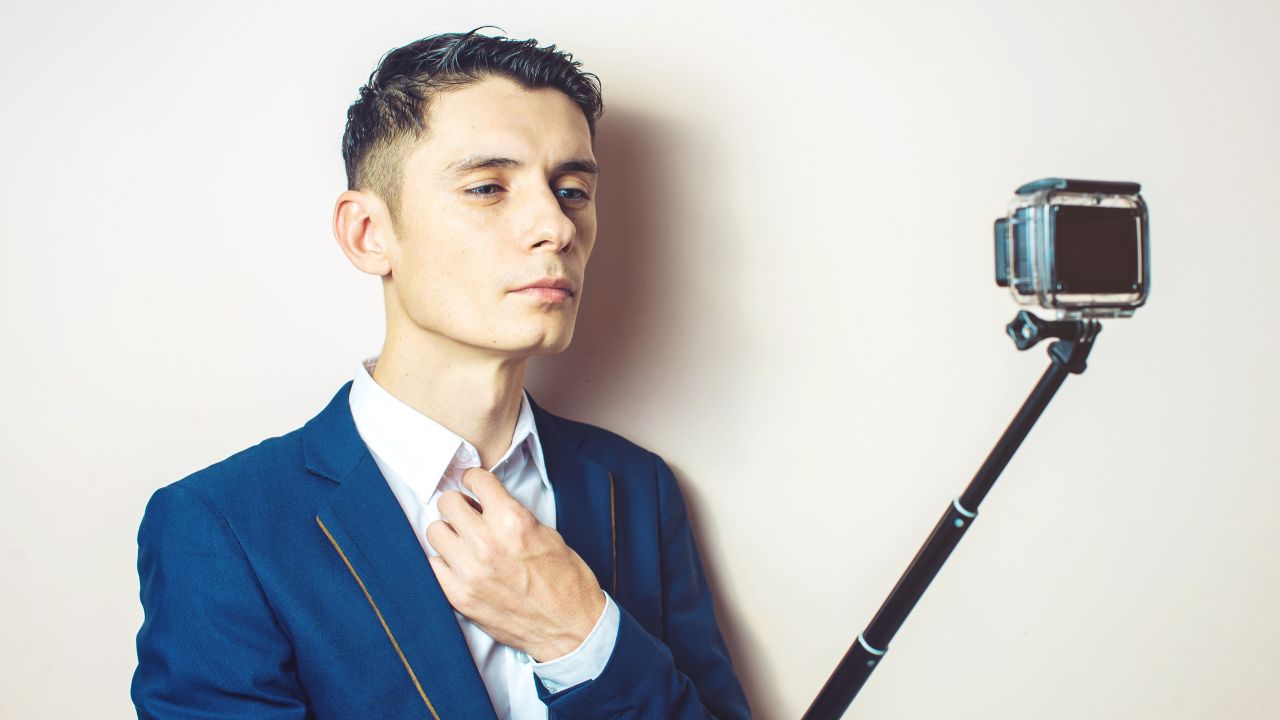 Young man in suit and tie with GoPro camera on a selfie stick